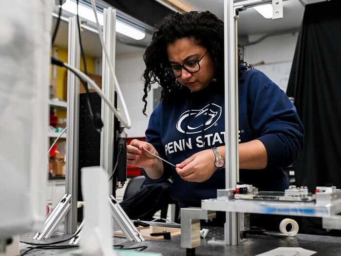 Postdoctoral scholar Sebanti Chattopadhyay prepares to load adhesive tape into the device. (Source: Jaydyn Isiminger/ Penn State)