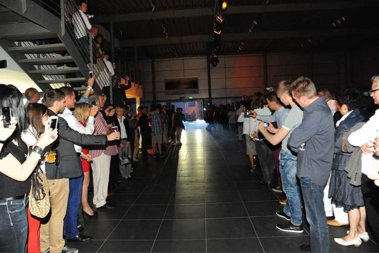 Zur Eröffnung in Recklinghausen hatte erstmals der 918 Spyder Hybrid seinen großen Auftritt – noch vor der eigentlichen Premiere auf der IAA. Gespannt warten die Gäste auf den großen Moment. (Foto: Hülpert)