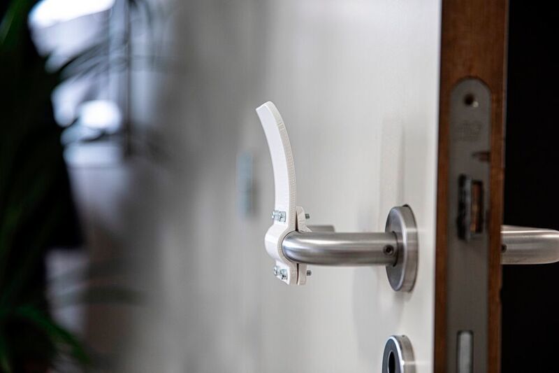 Materialise hat einen 3D-gedruckten Türöffner entwickelt, der es ermöglicht, Türen mit dem Arm zu öffnen und zu schließen. Ein direkte Kontakt mit den Türgriffen kann so verhindert werden. Das Unternehmen bietet die 3D-Datein kostenlos zum Download an. ((C) MATERIALISE)