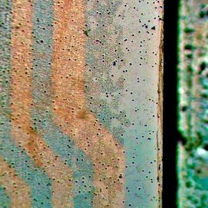 Das Bild zeigt in der Bildmitte die Laminat-Kante. Links ist der Blick durch den gebondeten Optical Stack mit sichtbar gemachtem PSA-Kleber und dessen Eigenschaften: schwarze Stellen zeigen massgeblich Blasenbildung und Partikel-Einschlüsse (mehr ist schlechter), beige Stellen in unterschiedlichen Helligkeiten zeigen die Dichte-Verteilung des Klebers, Rot , Grün und Blau in Pastell-Tönen zeigen die Oberflächen-Benetzung und Haftkraft  (mehr Farbe ist schlechter) und orange/bräunlich zeigen Leiterbahnen eines Touchsensors.  (Bild:  Wammes und Partner)