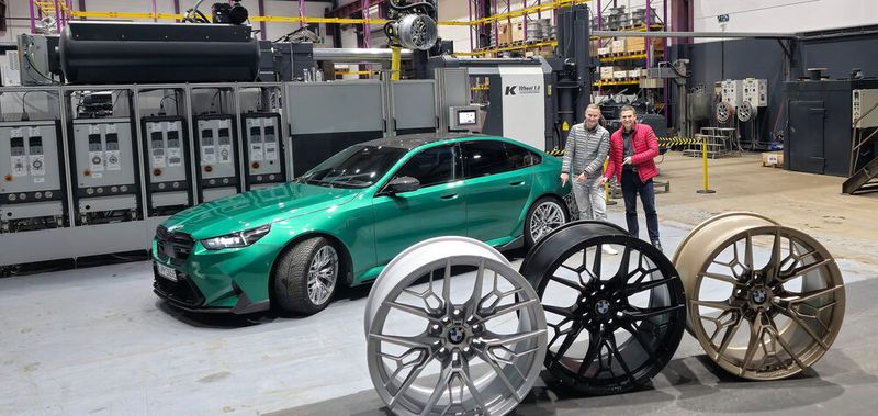 Im Vergleich zur herkömmlichen Produktion eines Pkw-Leichtmetallrads verringert sich der Energiebedarf bei dem vom Unternehmen Entec-Stracon entwickelten Herstellungsverfahren um die Hälfte, der Rohmaterialeinsatz um ein Viertel. Geschäftsführer Ralf Bux (rechts) und Mike Seidel, der Projektleiter Radentwicklung der BMW Group, deuten auf die bereits im Fahrzeug eingebaute Rad-Innovation. Die Deutsche Bundesstiftung Umwelt (DBU) hat das Projekt gefördert. (Bild:  Entec-Stracon )