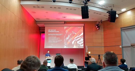 Im Konferenzprogramm berichtete unter anderem Florian Fischer von KTM-Technologies, wie Befestigungsklammern auf DLP-Maschinen von Genera in Serie additiv gefertigt werden.(Bild:  D.Quitter/VCG)