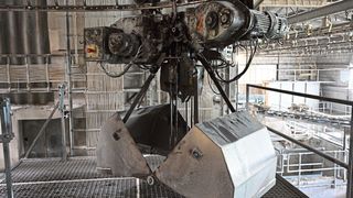 Entlang eines Schienensystems laufen Greifer, die nach und nach die Rohstoffkeller anfahren, bis das richtige Mischungsverhältnis des Pegmatitsands erreicht ist. Dabei trägt ein Greifer eine Last von etwa 350 Kilogramm. Dank der von BAM gefertigten Baugruppe haben sich Stillstandszeiten und Instandhaltungsarbeiten des Systems deutlich reduziert. (Shamika Löchel / BAM GmbH)