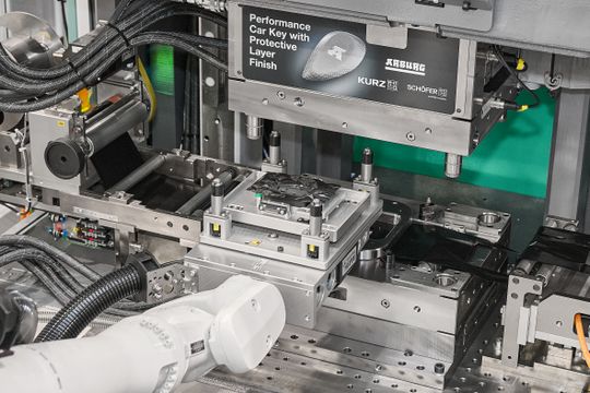 En el molde de la máquina de moldeo por inyección vertical, la lámina decorativa se recubre mediante inyección con material reciclado de PC/ABS.(Bild:  Arburg)