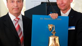 Mit den Worten „Möge sie nie zum Einsatz kommen“, überreichte Wolfgang Niedziella, Geschäftsführer des VDE-Instituts (links) dem Leiter des Brandprüfzentrums der VDE Prüf- und Zertifizierungsinstitut GmbH Detlef Staemmer, anlässlich der Eröffnung des neuen Testlabors eine Feuerglocke. (Reinhold Schäfer)