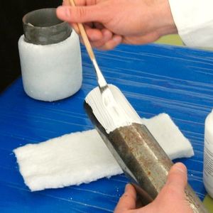 Auftrag des Keramikklebers Ceramabond 671 auf eine Metallrohr-Leitung zur anschließenden Ummantelung mit dem Keramikvlies Typ 3750.