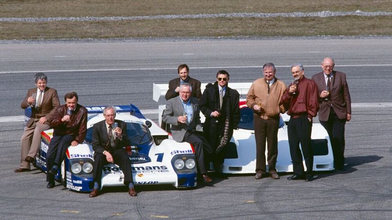 Siegertyp Porsche 956/962. Hier ein 962 C mit seinen Vätern Fritz Spingler, Valentin Schäffer, Peter Falk, Gerd Schmid, Helmut Schmid (dahinter), Hans Mezger, Norbert Singer, Horst Reitter und Eugen Kolb (v. l.). In den acht Jahren 1984 bis 199 fuhren die beiden Rennwagentypen rund 54 Siege und zahlreiche Meisterschaften ein. (Bild: Porsche)
