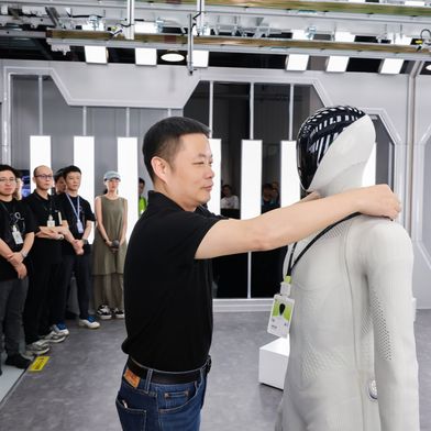 He Xiaopeng hangs an employee ID badge around the neck of the humanoid "IRON," as part of the team. (Source: Xpeng)