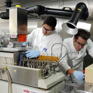 Mitarbeiter von Soliqs stellen Geräteparameter am Extruder ein. 