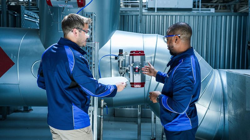 Zwei Beschäftigte von BMW an der „eRTO“-Reinigungsanlage für Abluft aus der Lackiererei.(Bild:  BMW)