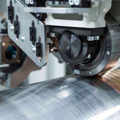 Am Fraunhofer IWS beschichtet man rotationssymmetrische Bauteile mit mehreren Metern Länge jetzt per Metallbandwicklung und Laserenergie. Der neue Prozess heißt Laserdirektplattieren und bringt viele Vorteile im Vergleich zum Laserauftragschweißen ... (Bild: Fraunhofer IWS)