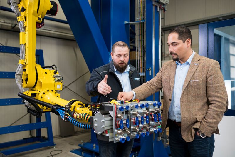 Rechtzeitig wurde auch die Roboter-Automatisierung für das Be- und Entladen der Trubend Center 7020 in Betrieb genommen. „Das bringt zusätzlich Tempo in den Produktionsprozess“, sagt Michael Kuipers (rechts) und Karsten Hanenkamp ergänzt: „Die Greifer legen Fertigteile auf bereitstehende Paletten zum Weitertransport in die Schweißerei.“ (Bild: Trumpf)