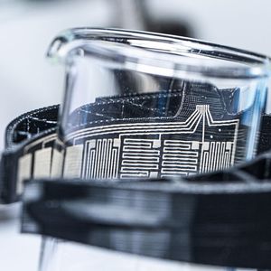 Hält gefühlvoll den Messbecher, statt ihn zu zerbrechen: Durch das Glas sind die integrierten Sensoren der BioGrip-Greifer zu sehen.(Bild:  Fraunhofer IWS)