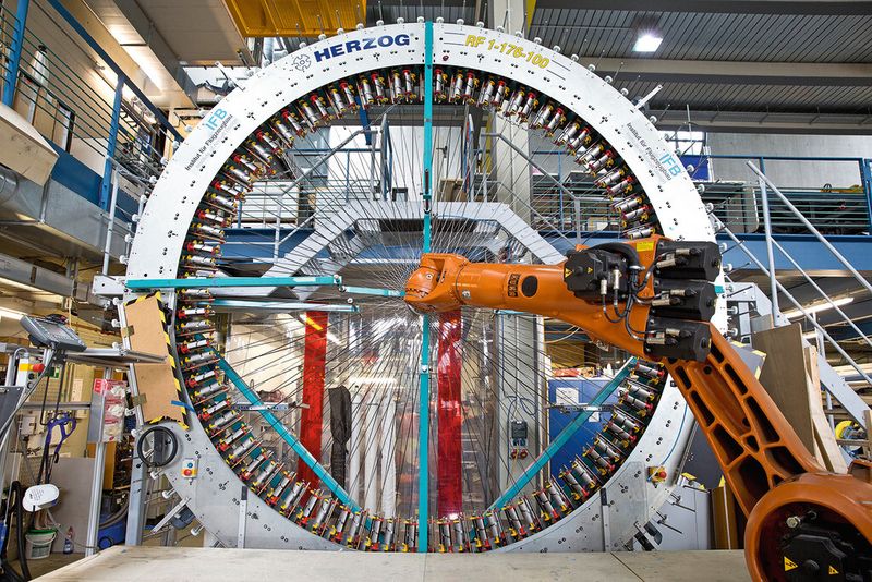 Ein Beispiel für die Herstellung von Leichtbau-Werkstoffen steht auf der Hannover Messe 2014 am Messestand des Instituts für Flugzeugbau der Universität Stuttgart. An dem mannshohen Flechtrad sind rundherum Spulen angebracht. Wenn es sich dreht, fügen sich 78 Fäden aus verschiedenen Fasern ineinander... (Bild: Universität Stuttgart)