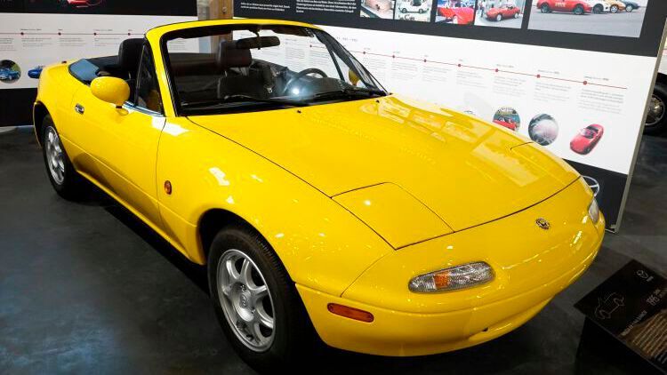 Er löste in den Neunzigern in zahlreichen Ländern eine Renaissance des Roadster aus: Mit einer Million verkauften Exemplaren ist der MX-5 der meistverkaufte Roadster weltweit. Vorgestellt wurde er 1989 und kam in Europa im Mai 1990 auf den Markt. Zunächst gab es nur einen 1,6-Liter-Motor mit 85 kW/115 PS. Geschaltet wurde das Fünfganggetriebe per sehr kurzer Schaltwege von 40 Millimetern. Sowohl die Vorder- als auch die Hinterräder waren einzeln an Doppelquerlenkern aufgehängt. An allen Rädern gab es Scheibenbremsen. Alles zusammen ermöglichte mit 50:50 eine ideale Gewichtsverteilung zwischen Vorder- und Hinterachse und machte den MX-5 zum echten Kurvenräuber. (Bild: Dominsky/»kfz-betrieb«)