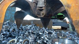 Wälzlager verschiedenster Bauarten und Größe werden vom Greifarm des Baggers unter lautem Getöse in die Schrottpresse befördert. (Bild: Schaeffler)