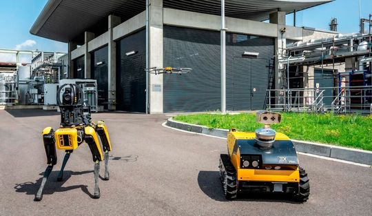 Eine Inspektionsdrohne, flankiert von zwei Inspektionsrobotern aus der Plattform von Energy Robotics, auf einem Shell‑Gelände in Rheinland(Bild:  Shell)