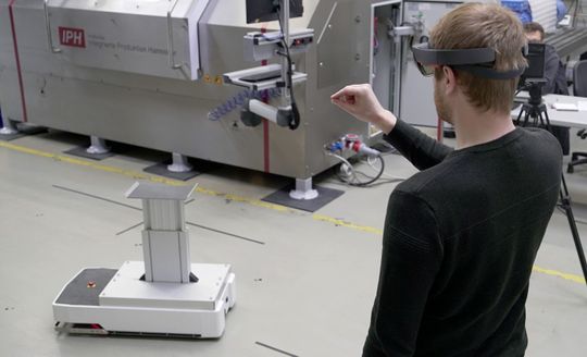 (Steuerung über Gesten: IPH-Mitarbeiter Viktor Schell bewegt das fahrerlose Transportfahrzeug mit einem virtuellen Joystick, der ihm über die AR-Brille eingeblendet wird. Foto: IPH, Beatrix Kamlage)
