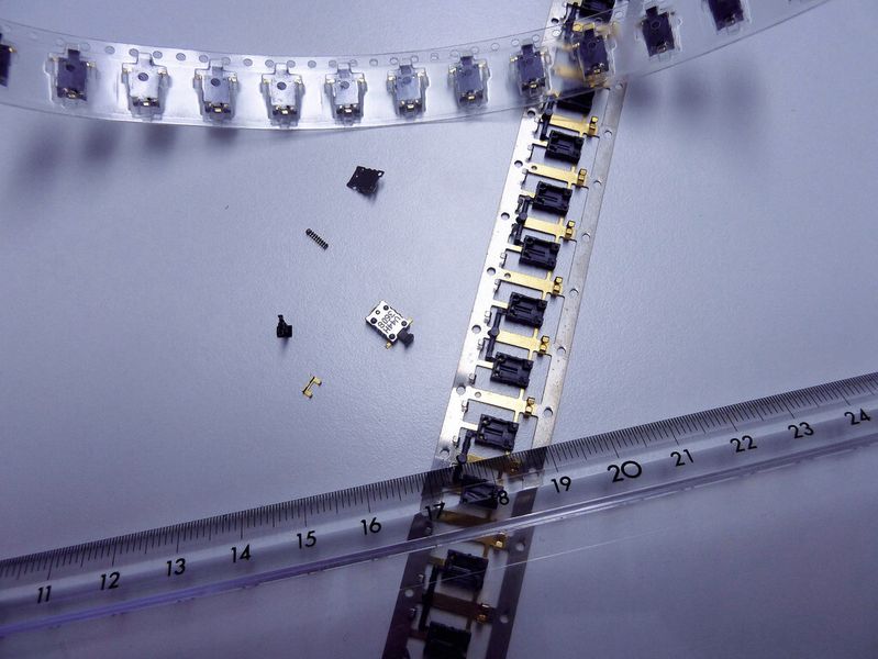 Millimeterarbeit! Mit den von Creative Automation entwickelten und gebauten Maschinen werden zahlreiche Mikrobauteile hergestellt, die mit den Fingern kaum greifbar sind und in einem Montageprozess zusammengeführt werden. Der Maßstab verdeutlicht die Größenordnung der Bauteile. (Bild: Kuhn)