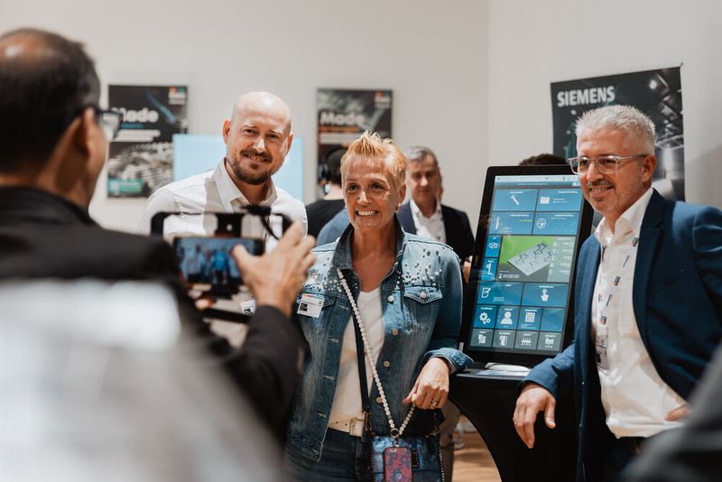 (from left to right) Paul Hanaman, Charlotte Breitwieser, Mustafa Ikeljic (Datron) in the exhibitor area at EMO Preview 2025  (Source: VDW/ Grainlab)