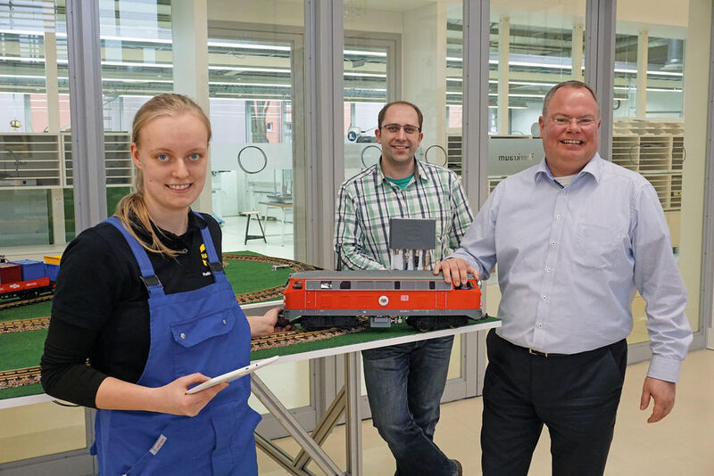 Adina Brandt (duale Studentin Maschinenbau) lässt sich anhand des Eisenbahnmodells die digitalen Zusammenhänge von Ausbilder Artur Maurer und Ausbildungsleiter Nico Gottlieb (rechts) erläutern.   (Harting)