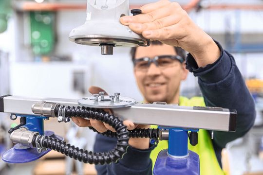 Versendet werden Schweißgeräte in Kartons. Um diese ergonomisch auf eine Palette zu heben, adaptiert der Werker einfach den Doppelsauger.(Bild:  J. Schmalz GmbH)