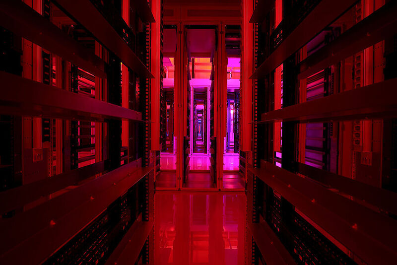 Der Blick durch den IT-Schrank auf die langen Reihen von Server-Racks. Das Bild zeigt das Rechenzentrum in Originalfarben. (ZWSY)