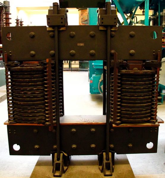 Erste Erdschlussspule von Petersen, 1917. Diese Spule zur Lichtbogenlöschung bei einpoligen Erdschlussfehlern an Freileitungen wurde 1917 behelfsmässig von Waldemar Petersen in das 11-kV-Netz der Kraftwerke Altwürttemberg AG in Ludwigsburg eingebaut. Nach erfolgreichen Versuchsbetrieb war diese Spule bis 1928 zur Erdschlusskompensation von Strömen bis zu 40 A in Betrieb. (Bild: DMM 67351 Erdschlussspule A / Dmm2va7 / CC BY)