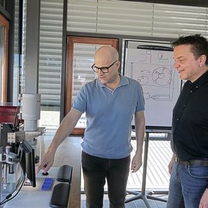 Thomas Villard zeigt Stephan Mack die Servo Presse PE20 High Precision. Sie ist die erste Maschine, die mit der Automatisierungslösung von Sigmatek ausgerüstet wurde.(Bild:  Lion Communication)
