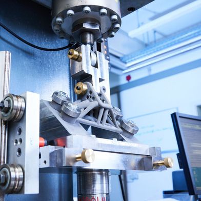 Zyklische Belastungsprüfung eines additiv gefertigten Metallbauteils nach einer mechanischen Oberflächenbehandlung an den hochbeanspruchten Zonen. Im Versuch wird der Lebensdauergewinn durch die Nachbehandlung getestet. (Bild: Fraunhofer IWM/Kai Wudtke)