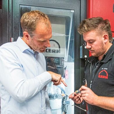 Kern Microtechnik fertigt die primär aus Edelstahl, Messing oder Arcap bestehenden Insertgehäuse der Glasfaserstecker kompromisslos präzise. Hier erklärt Alexander Stauder, Werkleiter der Kern-Auftragsfertigung, seinem Mitarbeiter, worauf es dabei ankommt. (Bild: Kern Microtechnik)