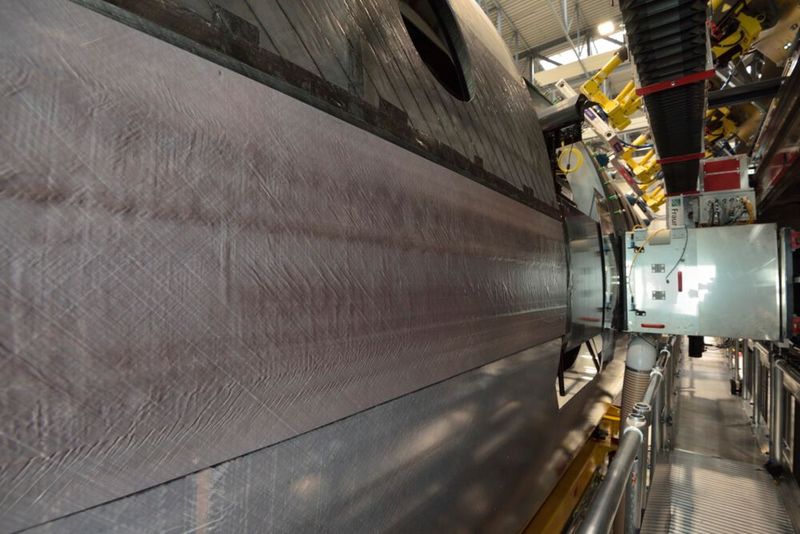 Thermoplastic CFRP butt strap connecting the two CFRP thermoplastic fuselage shells (on the left), joined by the CO2 laser welding end effector (right) in the MultiFAL assembly research platform (Image:Fraunhofer IFAM)