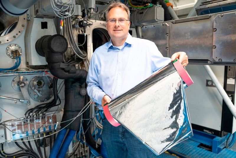 Projektleiter Claus Luber zeigt das Muster einer mittels Elektronenstrahlverdampfung mit Aluminium beschichteten Kunststofffolie. (Bild: Fraunhofer FEP, Finn Hoyer)