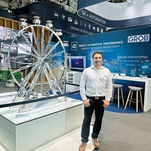 Sebastian Schön, sur le stand de GROB-WERKE devant la grande roue réalisée par les apprentis de l'entreprise spécialement pour l'AMB 2026.(Source :  Margaux Pontieu)