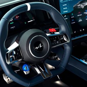 Am Lenkrad gibt es zwei farblich markante Knöpfe. Der blaue steuert die Stärke der Rekuperation, der rote die Boostfunktion.(Bild:  Alpine)