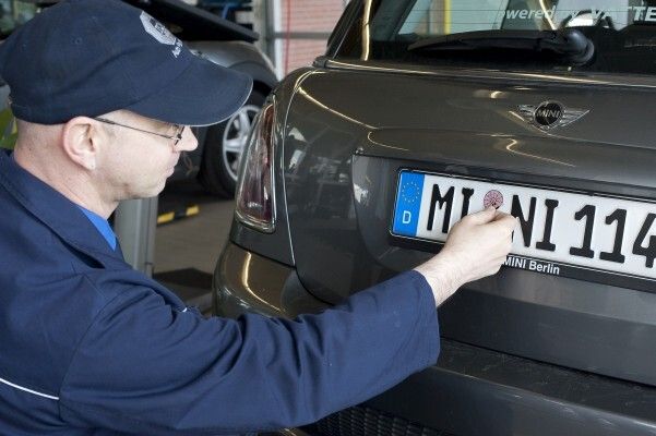 Prüfung bestanden: Nach erfolgreicher Hauptuntersuchung bring Thomas Praß die HU-Plakette am Mini E an. (Bild: TÜV SÜD)