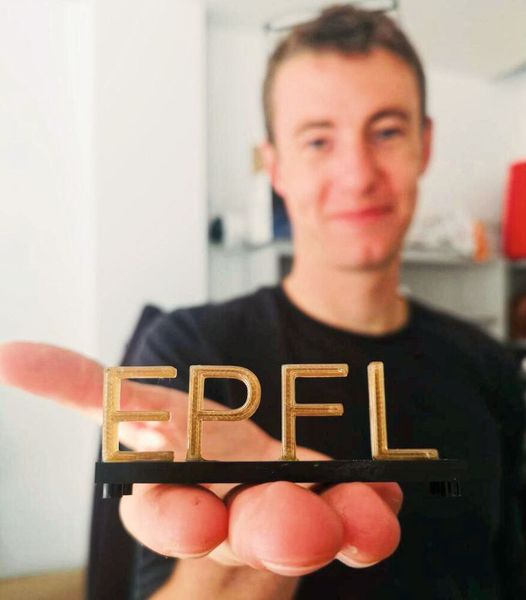 Lorenz Manker, le chercheur principal de l'étude, tenant un logo de l'EPFL imprimé en 3D avec le bioplastique. (Source : Stefania Bertella)