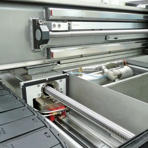 Die Microwaterjet-Maschinen verfügen über ein beidseitig gelagertes Portal, das über zwei Kugelrollspindeln angetrieben wird (im Bild). Für die Positioniergenauigkeit im Mikrometerbereich sorgen unter anderem Glasmaßstäbe über die volle Länge.