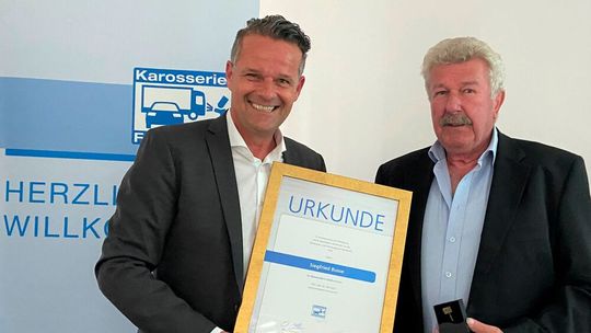 Obermeister Oliver Nienhaus (l.) übergibt die goldene Ehrennadel an Siegfried Busse.(Bild:  Innung Köln)