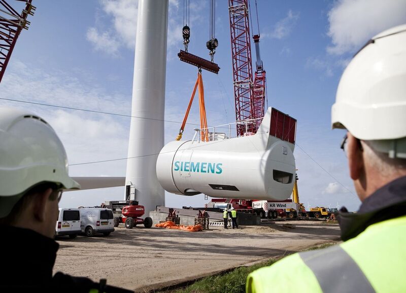 Die Gondel wird mit Hilfe eines Krans auf den Turm der Windenergieanlage gehoben. (Siemens)