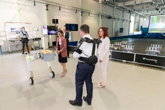 Politik trifft KI! Bundesarbeitsminister Hubert Heil (zwischen den Damen) testete bei seinem Besuch am Fraunhofer IML in Dortmund ein Exoskelett und begegnete dabei auch dem autonomen mobilen Roboter „evoBOT“. Lesen Sie hier, welchen Hintergrund der Besuch hatte.(Bild:  Fraunhofer IML)
