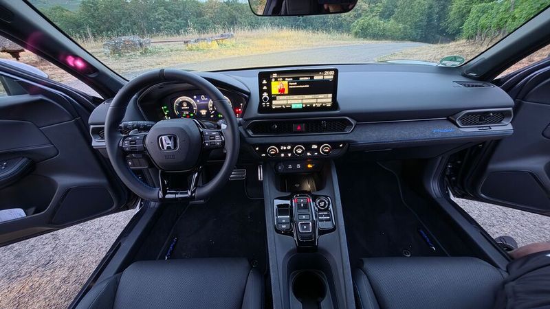 6. Der Innenraum: Honda macht Dinge gerne anders als andere Hersteller. Das gilt auch für den Innenraum. Während man in immer mehr Modellen alle Funktionen über den zentralen Tochscreen steuern muss, gibt es im Honda nach wie vor ganz klassische Drehschalter und Tasten, beispielsweise für die Klimatisierung oder die Spiegeleinstellung. Das erleichtert die Bedienung deutlich. Lediglich das Lenkrad ist mit Tasten etwas zu überlastet. Auch der Touchscreen in der Mittelkonsole ist mit 9 Zoll im Verhältnis zu anderen aktuellen Fahrzeugmodellen eher klein dimensioniert. Die Verarbeitung  im Prelude ist makellos, die Wahl der Materialien ist gelungen. Hartplastik findet sich kaum im Interieur. Bemerkenswert ist, dass man trotz der geringen Höhe des Prelude und der abfallenden Dachlinie kein beengtes Raumgefühl hat. Einen kleinen Abzug in der B-Note gibt es für die nicht wirklich attraktive Gestaltung des Tasten-Gangwahlschalters. Für ein Sportcoupé wäre ein Wählhebel authentischer gewesen. (Bild: Mauritz – VCG)