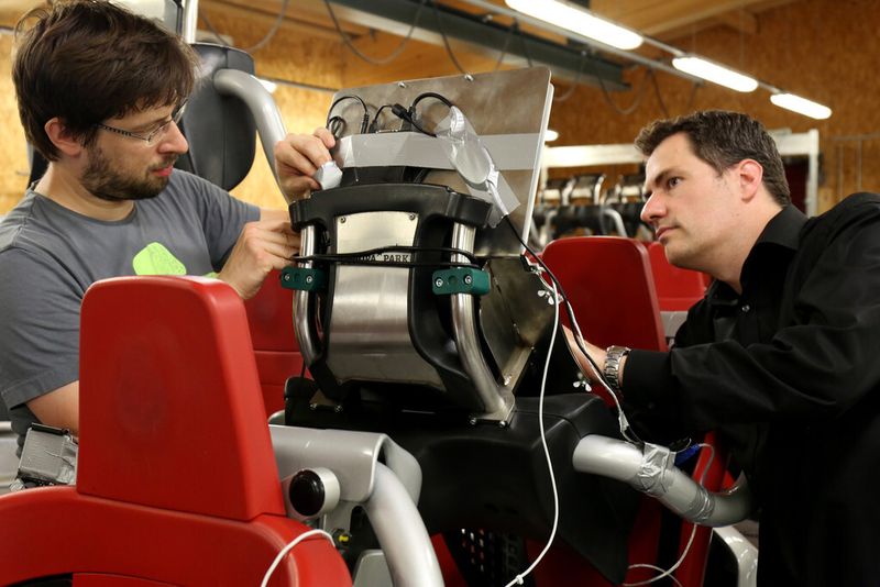 Prof. Thomas Wagner (rechts) und der Lehrbeauftragte Michael Heyse (links) montieren ein Laptop an einem Sitzplatz der Achterbahn „Blue Fire“. (FH Kaiserslautern)