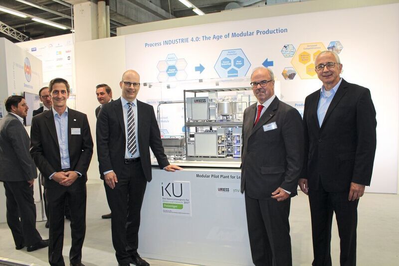Von links nach rechts: Dr. Christoph-Fleischer-Trebes (Invite), Dr. Thomas Brackemeyer, Dr. Wolfgang Podesta und Dr. Joachim Waldi (alle Lanxess) vor dem Modell der Reel-Pilotanlage (Geipel-Kern/PROCESS)