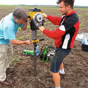 Schweres Geschütz: Stefan Dreibrodt (l.), der mit der Hilfe eines Studenten und eines Benzinhammers eine Bohrsonde in den Boden abteuft. (Bild:  Sebastian Schultrich, Uni Kiel)