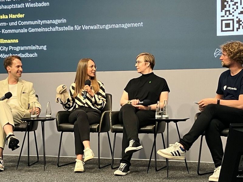 Dass gemeinsamer Austausch wichtig sei, betonten Jan Klumb (v.l.n.r.), Kira Tillmanns, Smart City Programmleiterin in Mönchengladbach, Franziska Harder, Plattform- und Communitymanagerin bei der Kommunalen Gemeinschaftsstelle für Verwaltungsmanagement (KGSt), und Dr. Niklas Kossow, Bereichsleiter Smart City & Verwaltungsinnovation beim CityLAB Berlin (hier als Moderator). Tillmanns brachte zu dieser Diskussionsrunde ein kleines Maskottchen mit – „den Jammerlappen“: „Jammern ist der erste Schritt zur Innovation“. Zum Thema „Blaupause Zukunft: Wenn gute Ideen auf Reise gehen“ sagte sie, es sei wichtig, einfach mal zu machen und das Jammern zu teilen.  (Bild: Serina Sonsalla / Vogel IT-Medien)