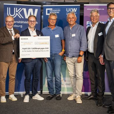 Beim „Würzburger Tag der Zukunftsmedizin“ an Bord der MS Wissenschaft überreichte die Vogel Stiftung einen Scheck über drei Millionen Euro zur Unterstützung der CAR-T-Zellforschung an das Team von Prof. Michael Hudecek vom Universitätsklinikum Würzburg. V.l.n.r.: Prof. Dr. Matthias Frosch, Prof. Dr. Hermann Einsele, Prof. Dr. Michael Hudecek, Rolf Lenertz, Prof. Dr. Michael Müßig, Dr. Gunther Schunk, Prof. Dr. Tim J. von Oertzen (Bild: Thomas Berberich / UKW)
