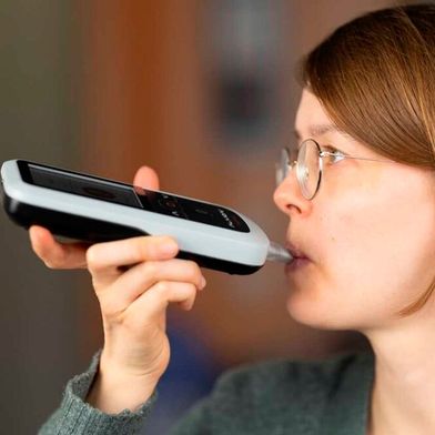 Eine Nutzerin führt mit dem smartphoneunterstützten Aceton-Atemanalysator eine Messung durch. (Bild: Alivion AG)