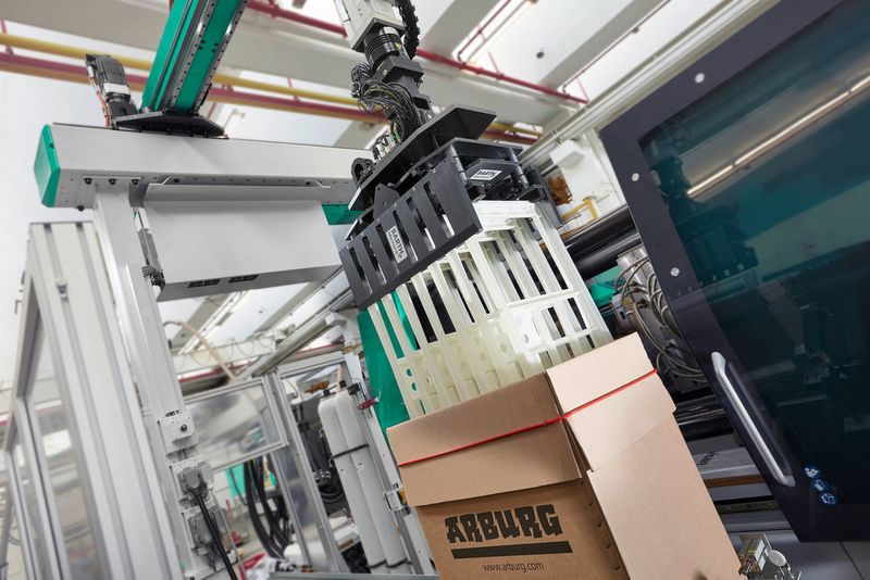 Eine Turnkey-Systemkomponente, die auf der Fakuma in Aktion zu sehen ist, ist dieser Multilift V 40, der gespritzte Teile zunächst in einer Zwischenablage magaziniert. Wenn sieben dieser Gehäuse fertig sind, übernimmt er auch das Kartonieren. (Arburg)