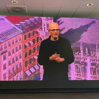 „Wir wollen jeden einzelnen leistungsfähiger machen und neue Möglichkeiten erschließen“: Microsoft-CEO Satya Nadella wurde aus den Eisbachstudios per Videoschalte in die Pressekonferenz übertragen. Im Hintergrund ein Foto des Münchner Marienplatzes. (Bild: Rüdiger)